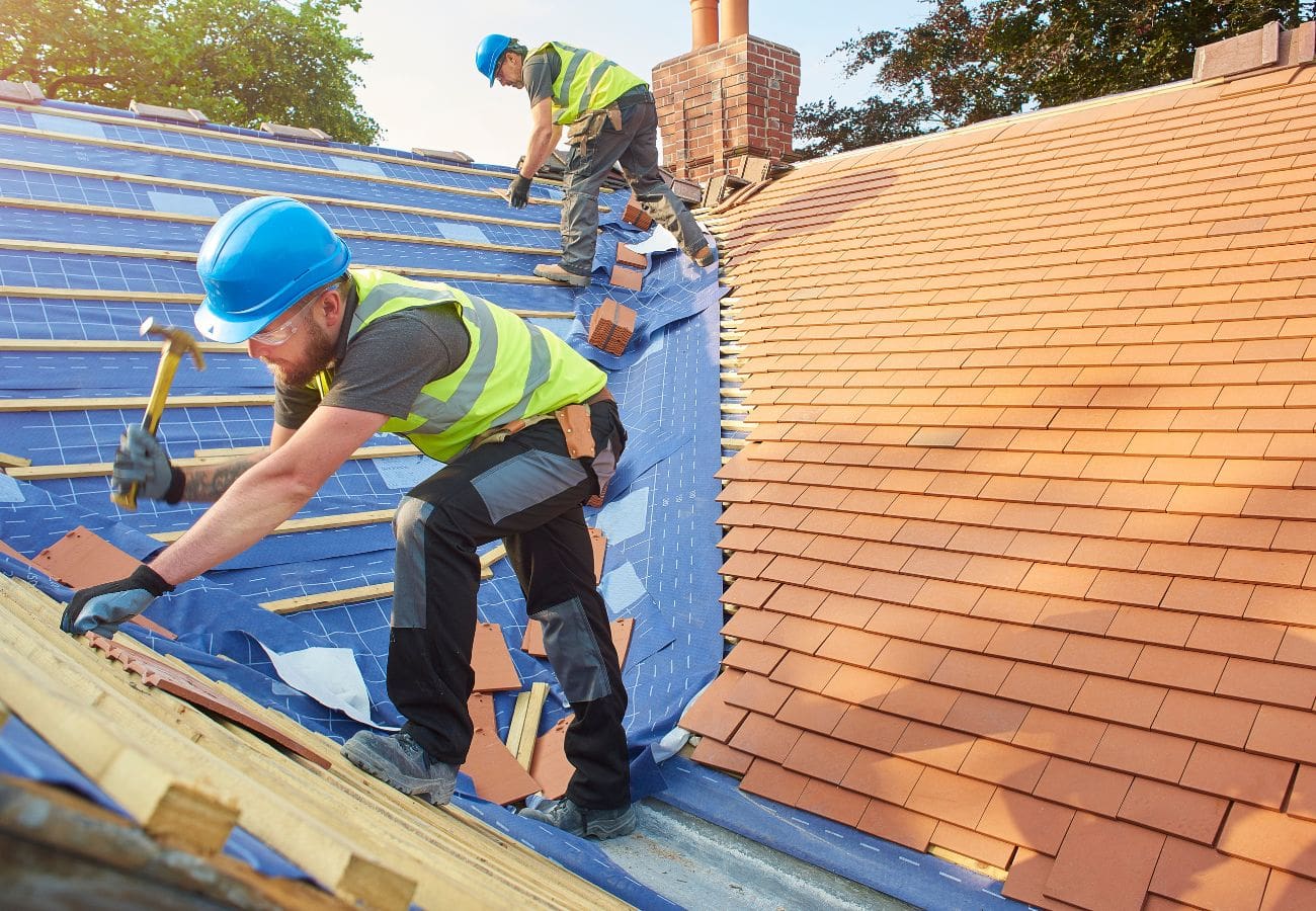 Two men installing new roof shingles